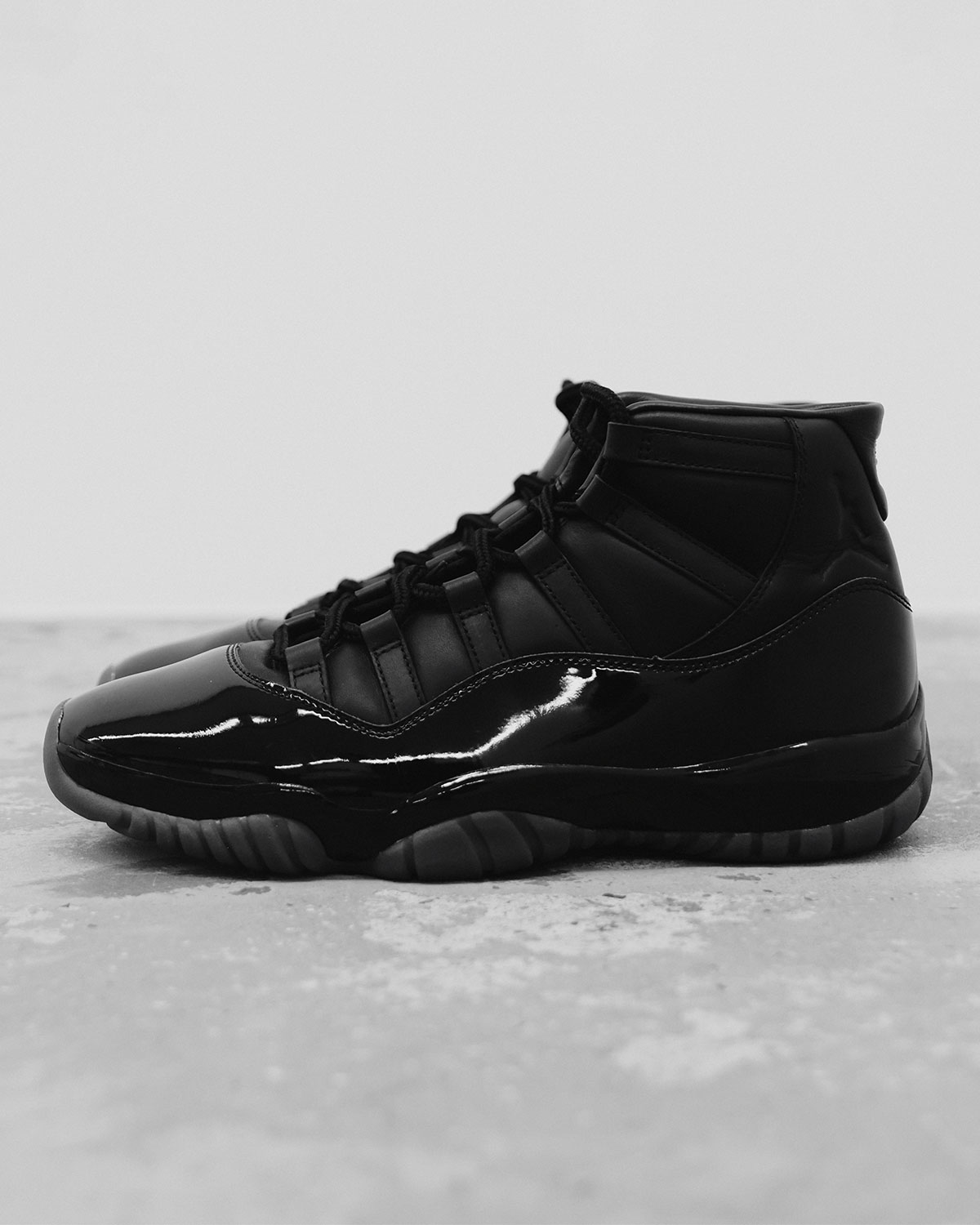 Comme des Garçons Homme Plus × Air Jordan 11 noire IV7639-001, vue de profil sur béton