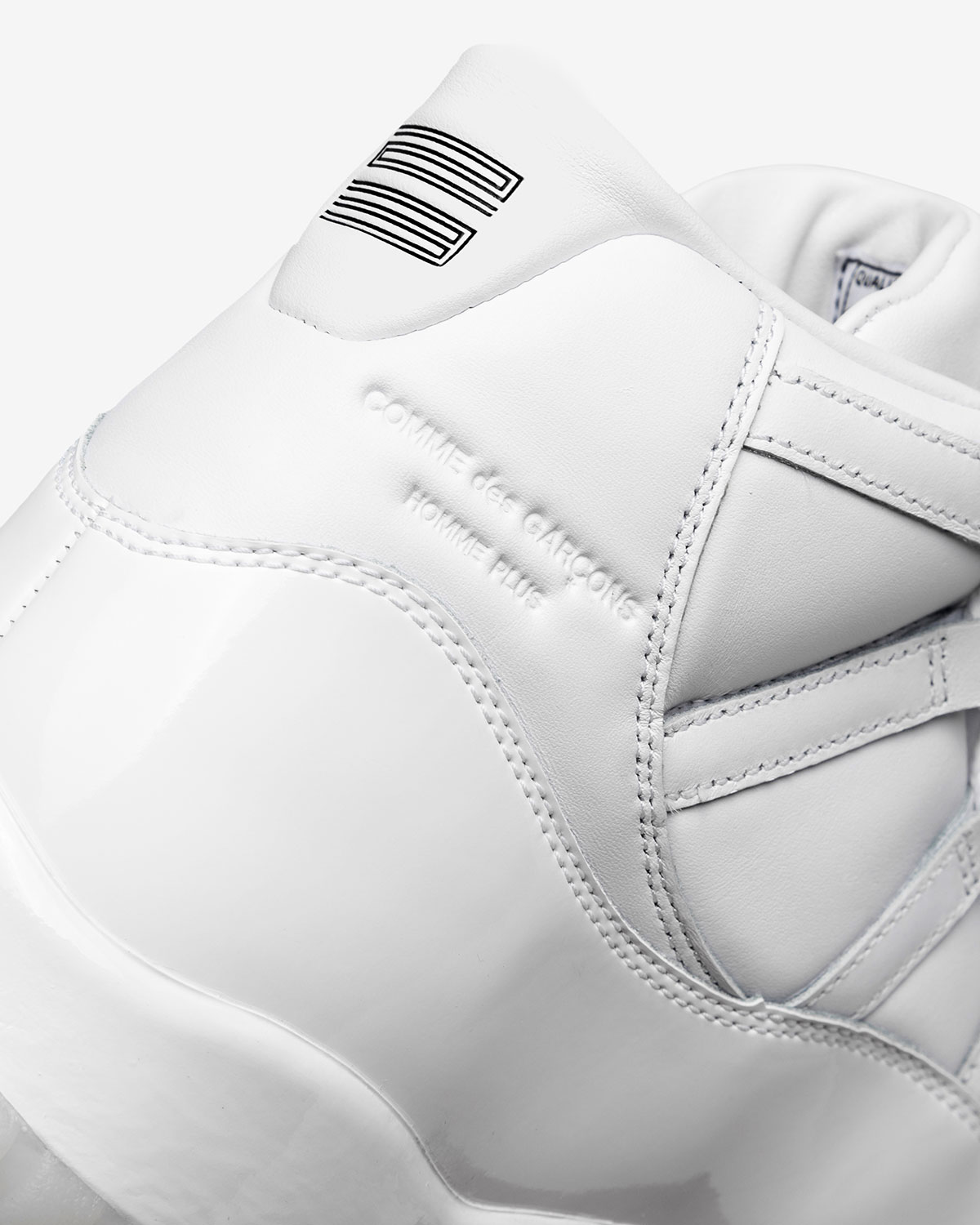 Détail du talon de la Comme des Garçons × Air Jordan 11 blanche, mention Homme Plus embossée dans le cuir